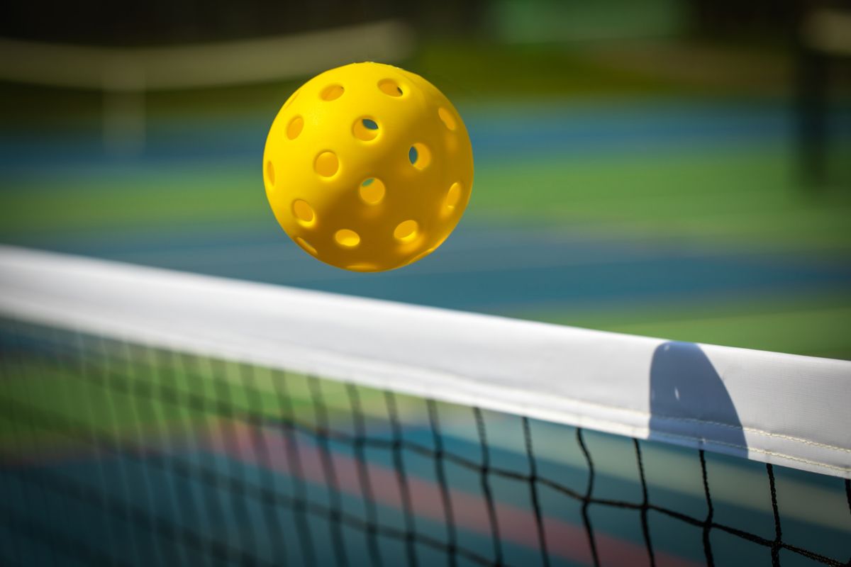 Pickleball ball flying over a net