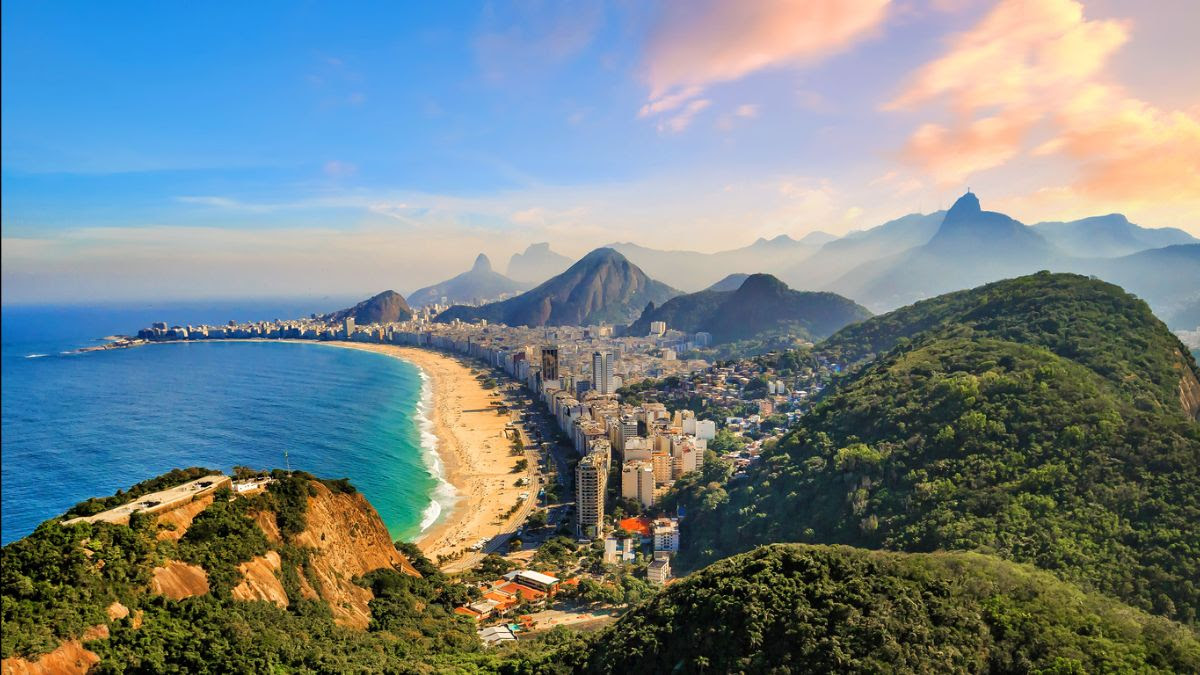 A birds-eye view of Copacabana Beach in Rio de Janeiro, Brazil, showcasing the urban landscape next to the beach and mountains in the distant background 