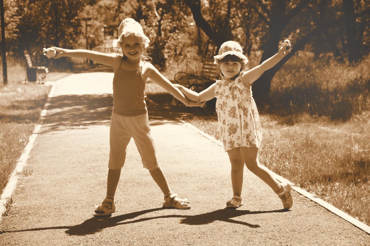 Sepia-toned photo of two children holding hands on a park path representing nostalgia, memory, and the emotional value of revisiting meaningful life moments.