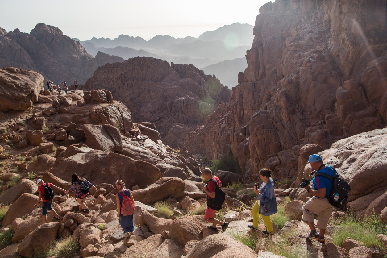 An aerial view of group of hikers hiking along a rocky mountain top  