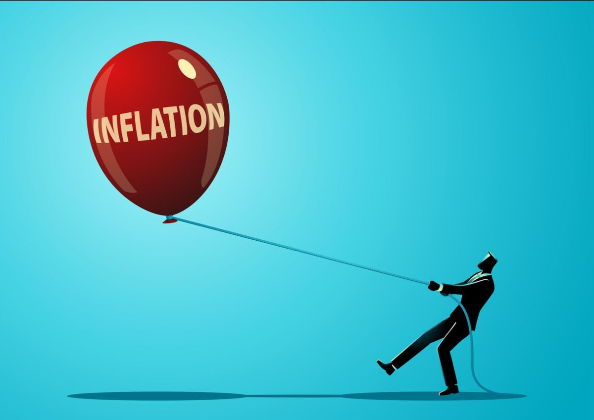 An “illustration of a person in a suit struggling to hold onto a rope tied to a large red balloon labeled ‘INFLATION’ against a bright blue background.”