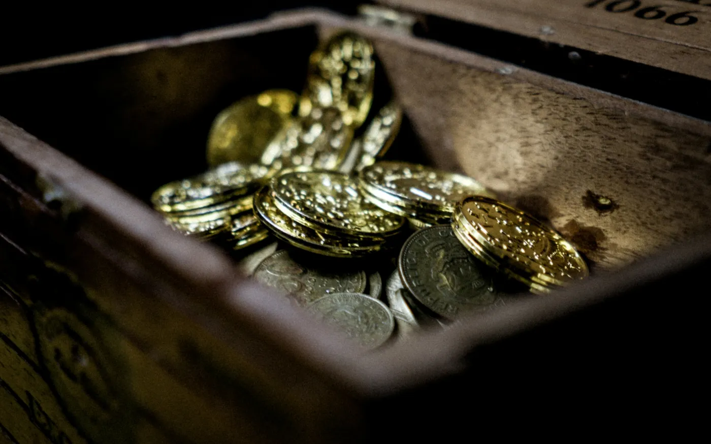 a wooden box filled with lots of coins by Bjorn Pierre courtesy of Unsplash.