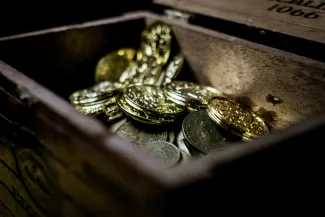 a wooden box filled with lots of coins by Bjorn Pierre courtesy of Unsplash.